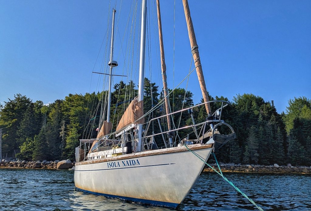 Isola Naida tied up to a mooring ball at South Shore Marina flanked by trees on the shoreline in the backgroound.